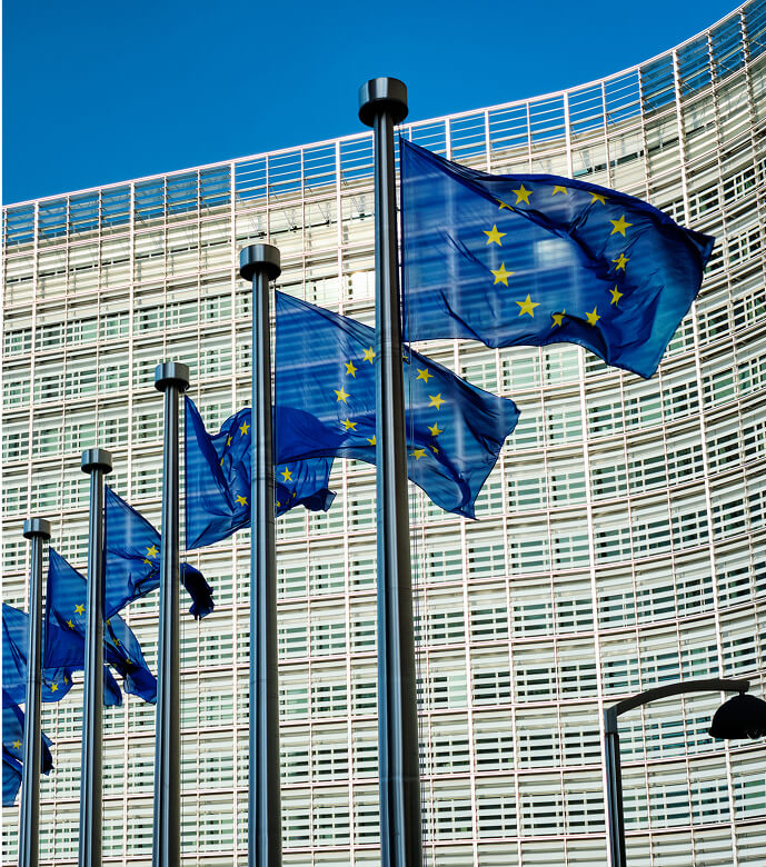 Flagi Unii Europejskiej powiewające przed nowoczesnym budynkiem